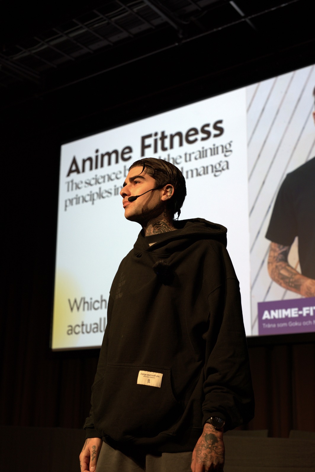 Man looking at the audience in front of lecture stage with a microphone set.