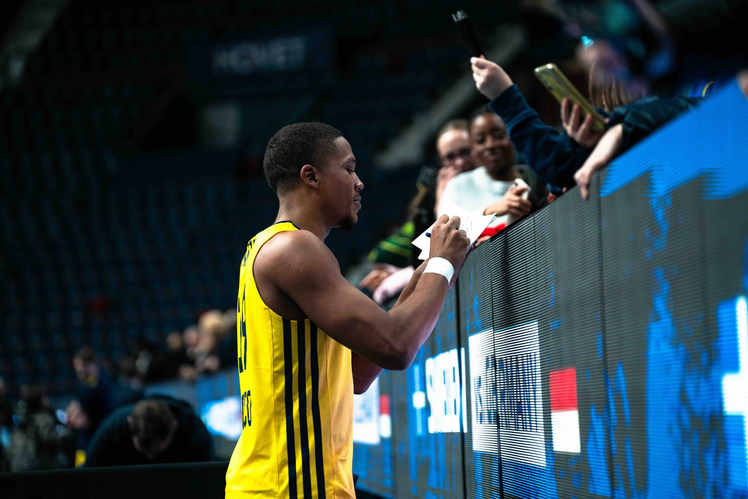 basketball player signing autograph for fans on the court