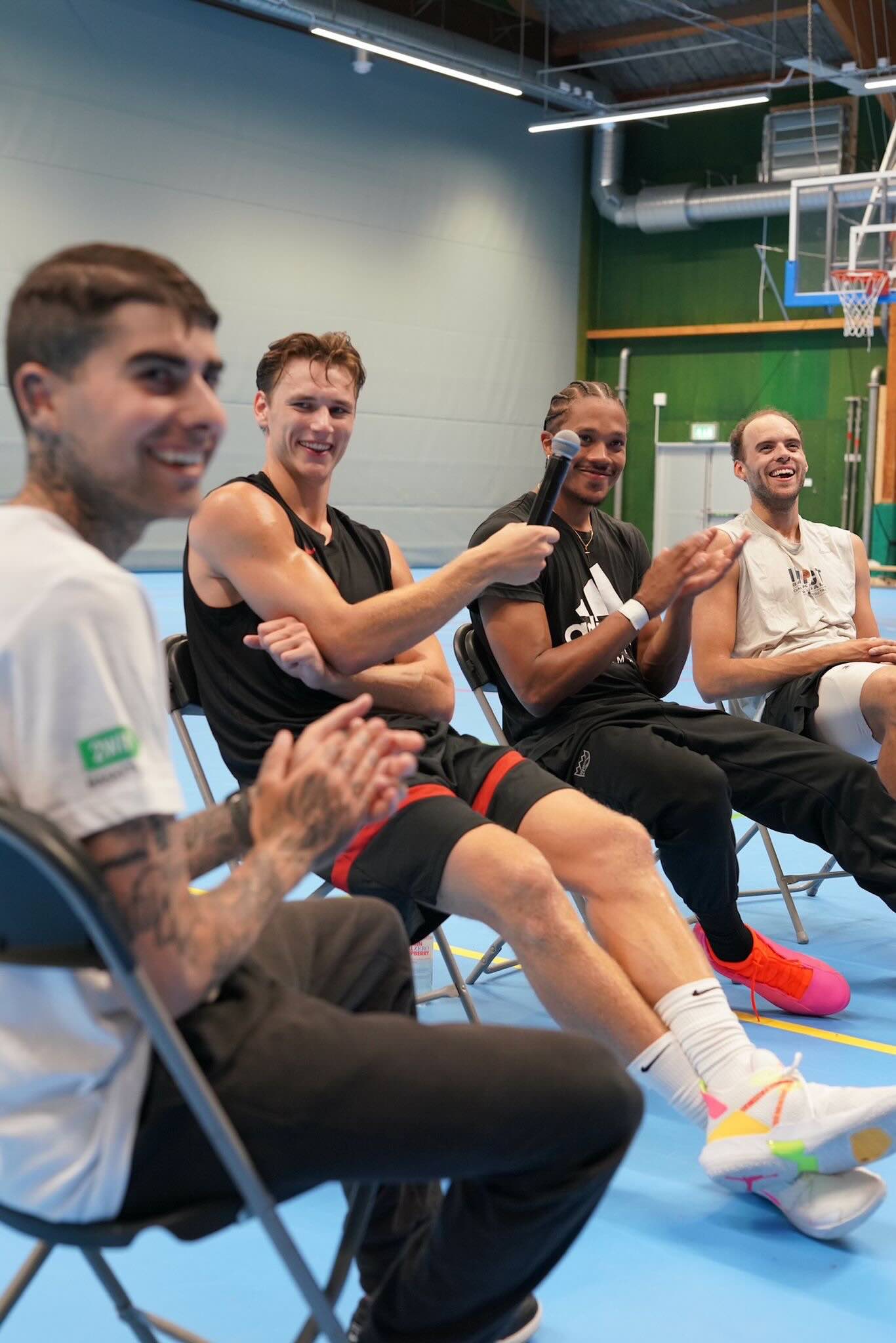 Three basketball players people sat on chairs being interviewed by moderator